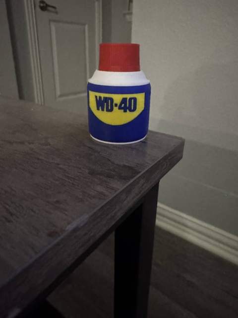 Elliott's 3D printed clicker that looks like a WD-40 can, in blue, yellow, white and red